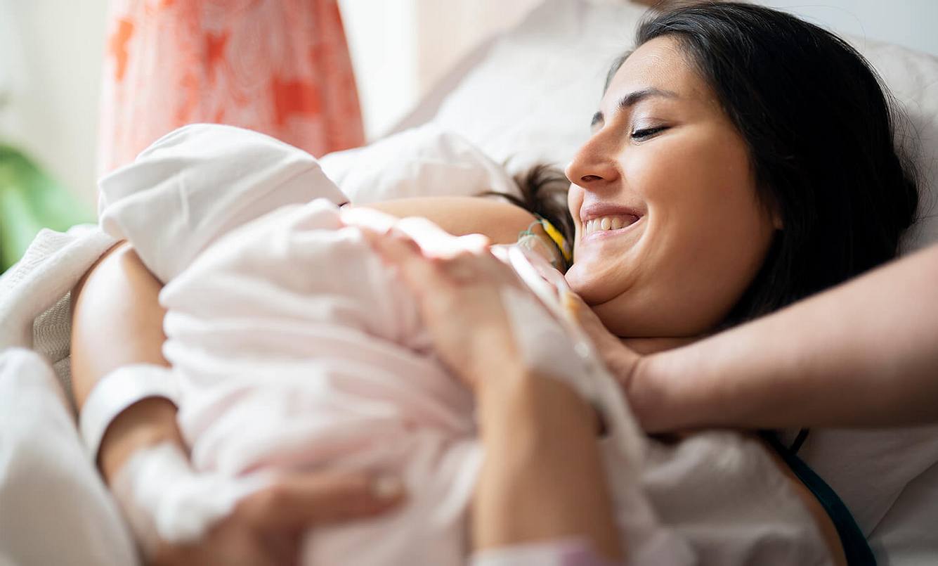 Eine Mutter mit ihrem Baby im Arm kurz nach der Entbindung