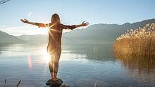 Junge Frau umarmt Natur am Bergsee - Foto: iStock/swissmediavision
