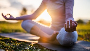 Frau macht Yoga bei Sonnenaufgang - Foto: iStock/Marija Jovovic
