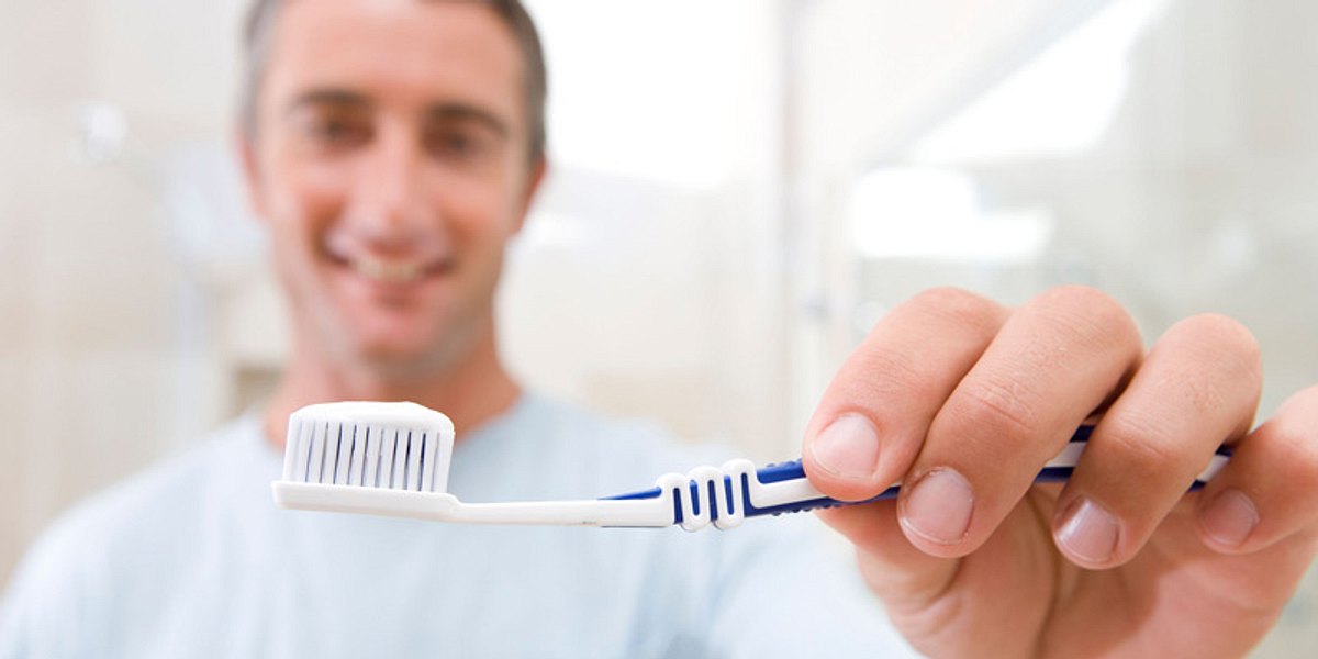 Mann zeigt Zahnbürste