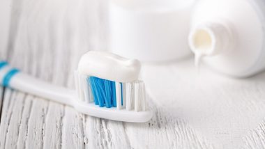 Zahnbürste mit Zahnpasta und offene Tube auf Holztisch - Foto: iStock-1079823382 AndreyCherkasov