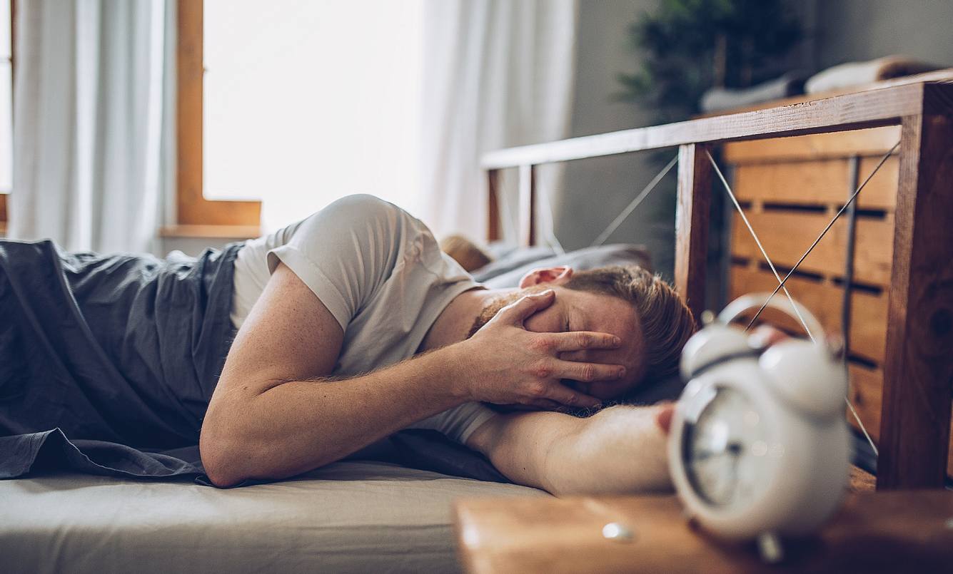 zeitumstellung-im-sommer-gesundheitliche-folgen Mann macht seinen Wecker aus