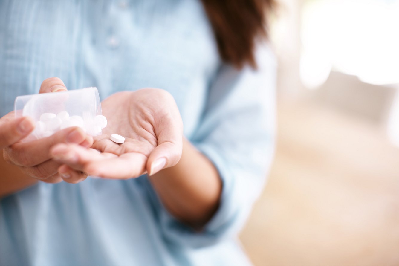 Eine Frau schüttet sich Tabletten auf die Hand