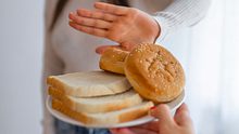 Eine Frau weist einen Teller mit Brot, der ihr angeboten wird ab. - Foto: iStock / dragana991