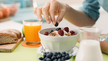 Frau isst gesundes zuckerfreies Frühstück mit Müsli und Beeren - Foto: iStock/demaerre