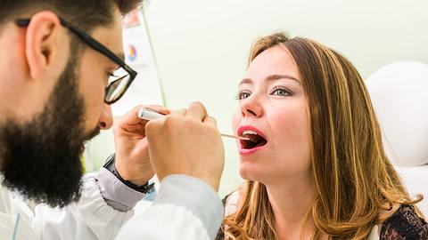 Arzt untersucht Mundhöhle einer Frau - Foto: iStock-478530412 massimofusaro