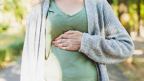 Eine Frau hält ihre Hand auf ihren Oberbauch - Foto: iStock/Madrolly