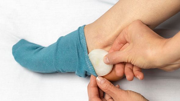 Frau legt eine Zwiebel in die Socke - Foto: iStock/Oleksandr Todorov
