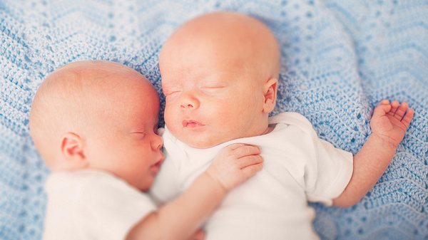 Zwillingsbabys liegen sich in den Armen - Foto: istock/lpettet